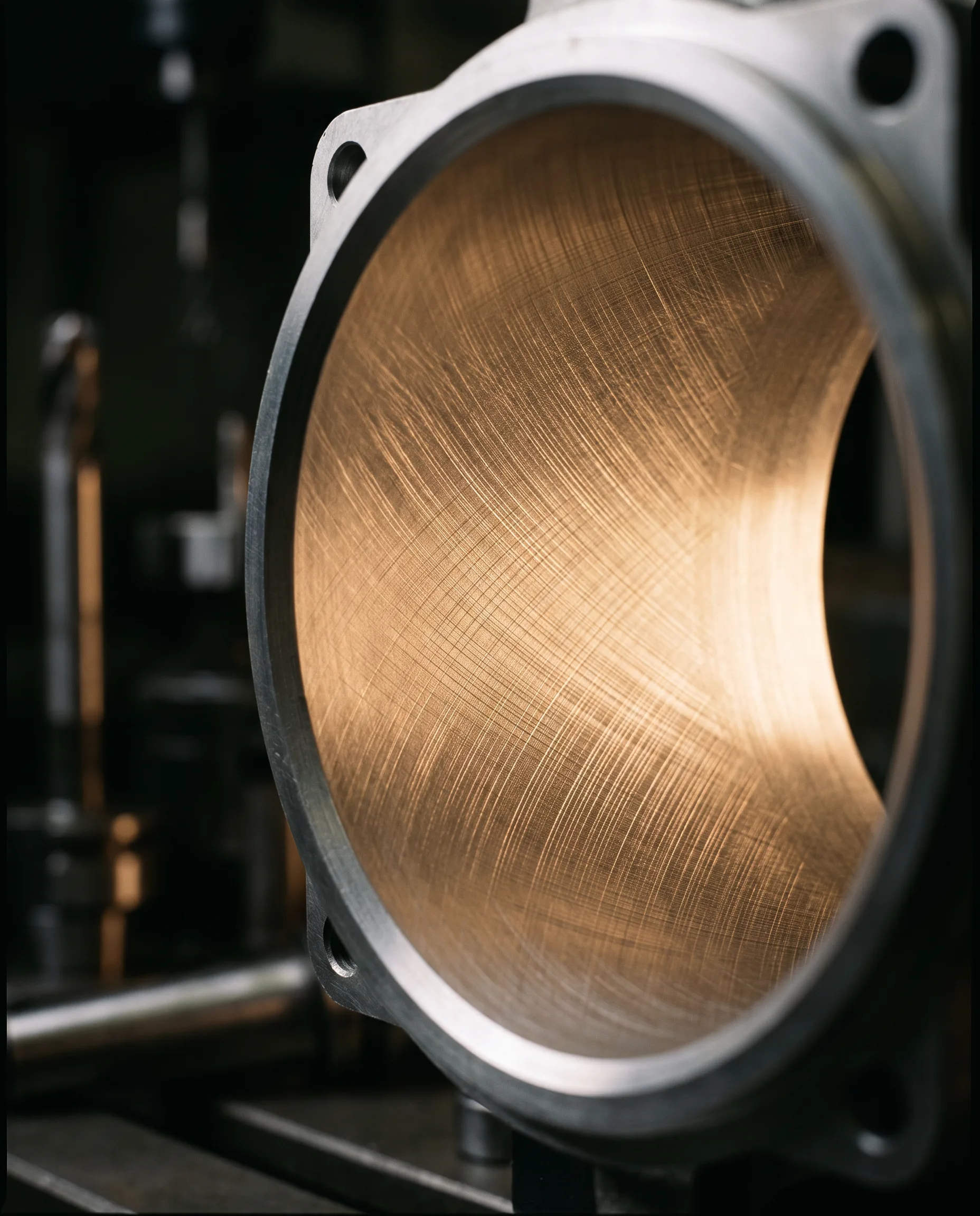 A honed bore seen down its axis in a flanged aluminum housing, a fine even cross-hatch running the full circumference.